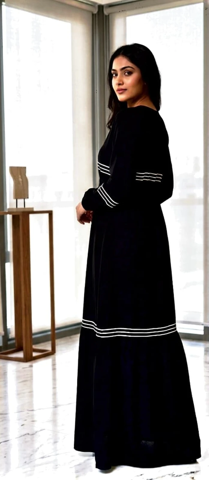 Woman wearing a black full-length abaya dress with white stripe details and a matching hijab