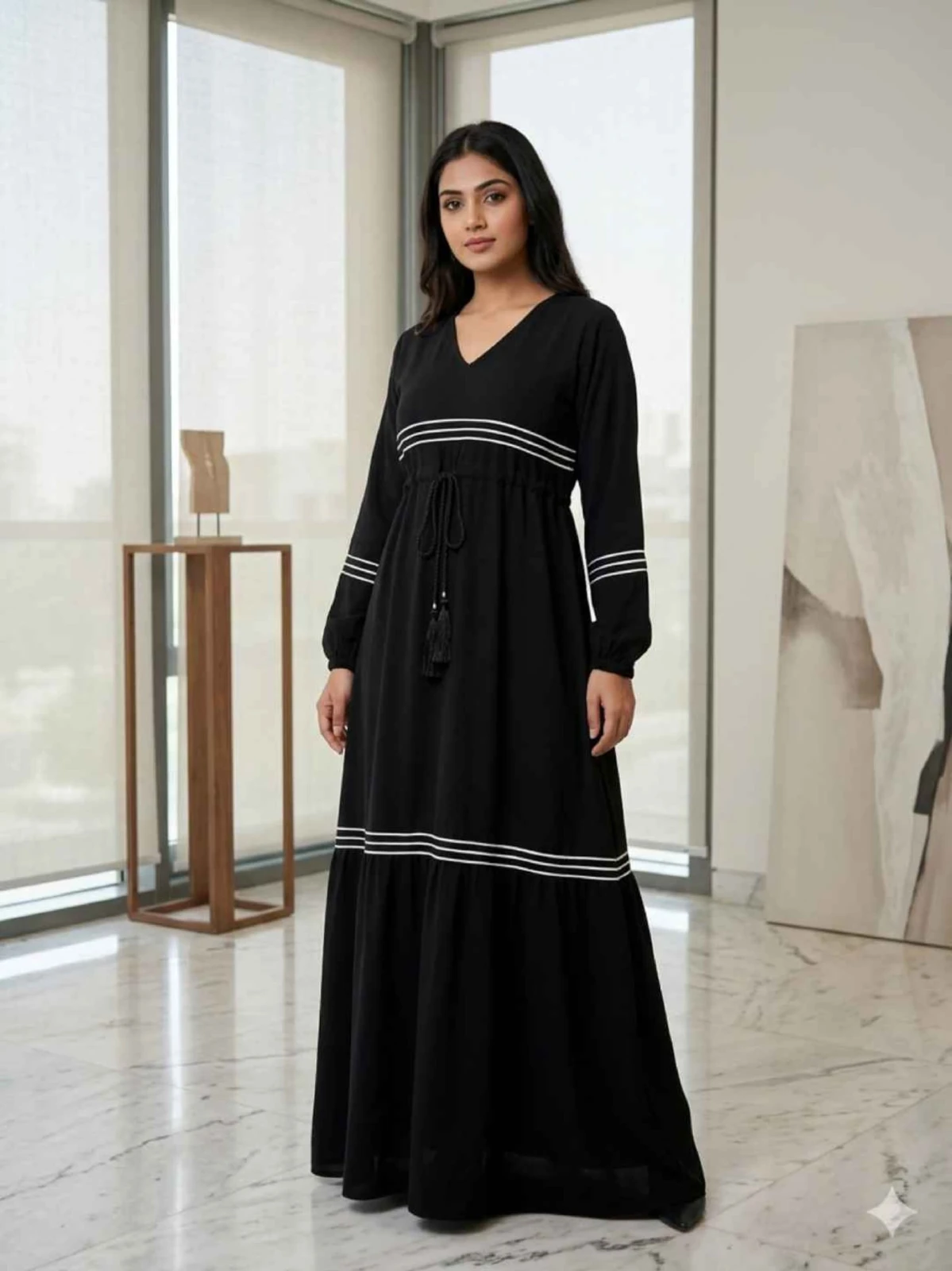 Woman wearing a black full-length abaya dress with white stripe details and a matching hijab